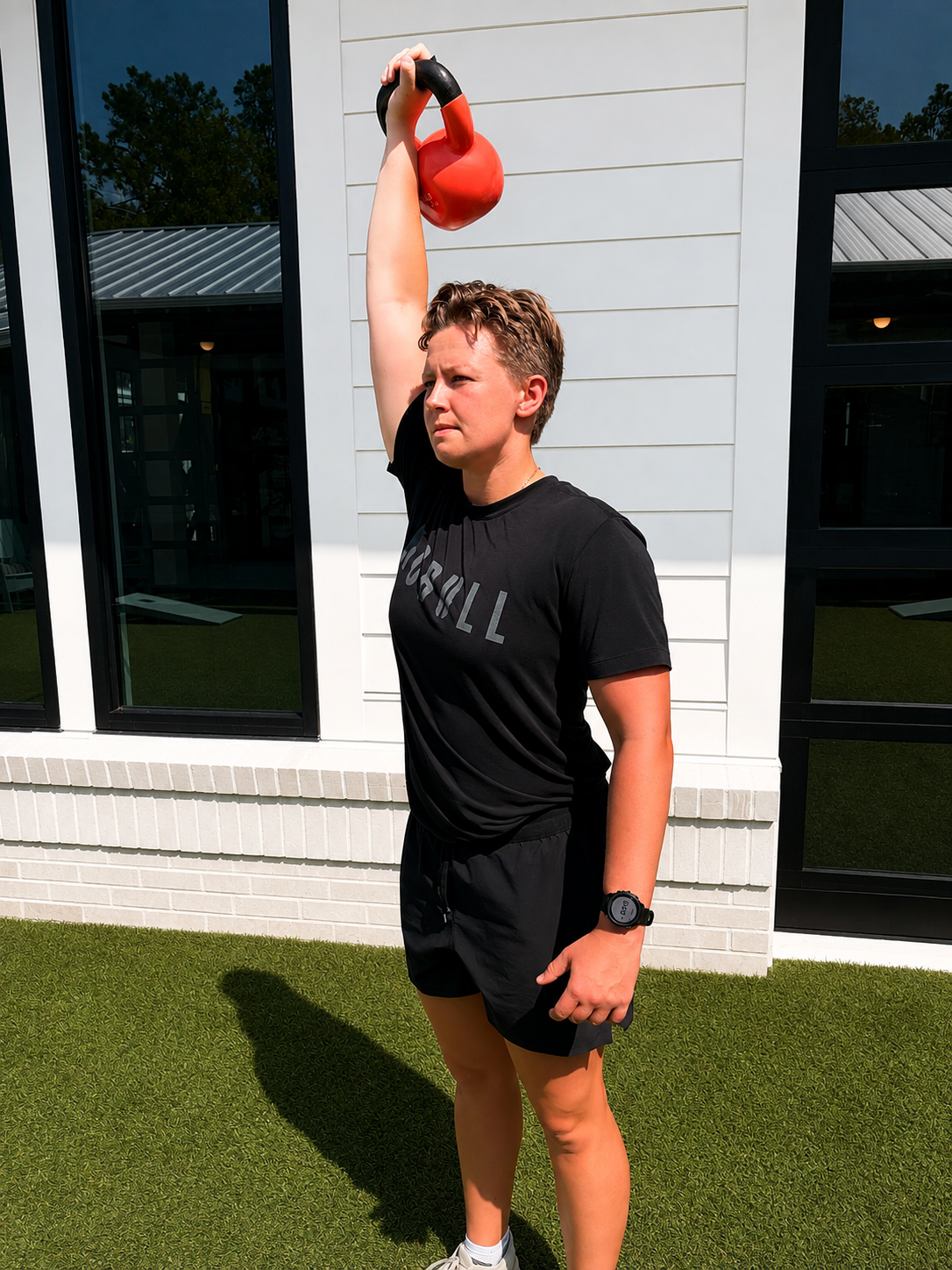 Coach Hannah Brown Trice demonstrating an overhead kettlebell exercise in Wilmington, NC
